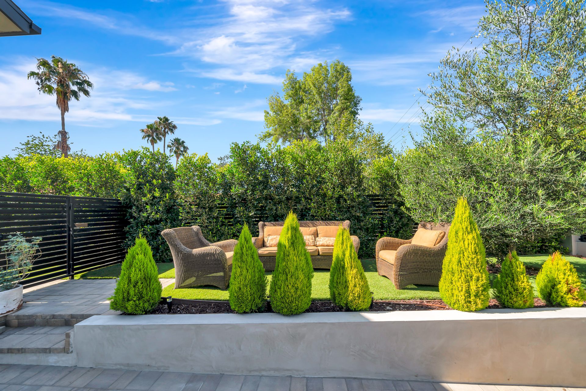 Landscaped outdoor lounge with planters and hedging